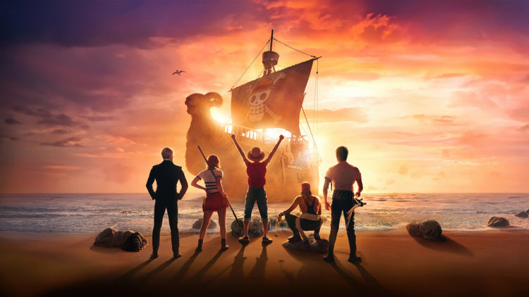 The crew of the Straw Hat Pirates, including Monkey D. Luffy with his arms raised, stand on a beach looking out at their pirate ship, the Going Merry, against a vibrant golden sunset.